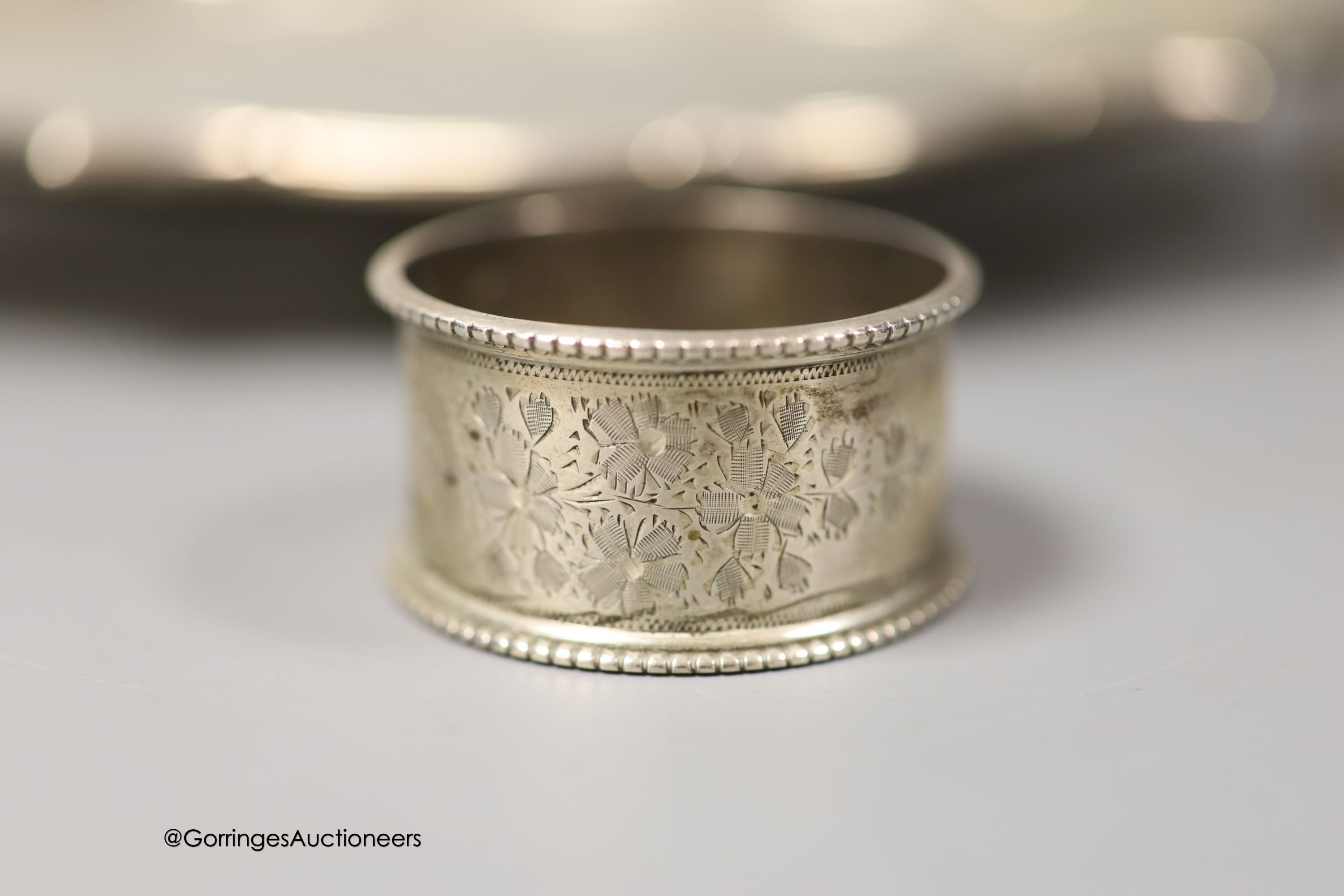 An Edwardian silver shaped circular salver, Goldsmiths & Silversmiths Co Ltd, London, 1902, 25cm and three silver napkin rings